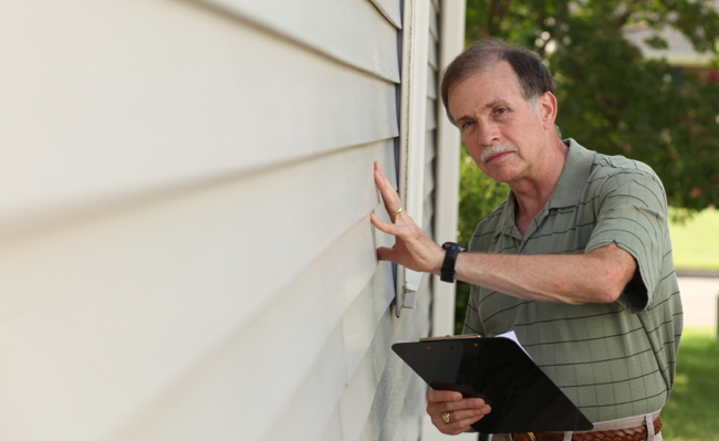 Adult male inspects siding